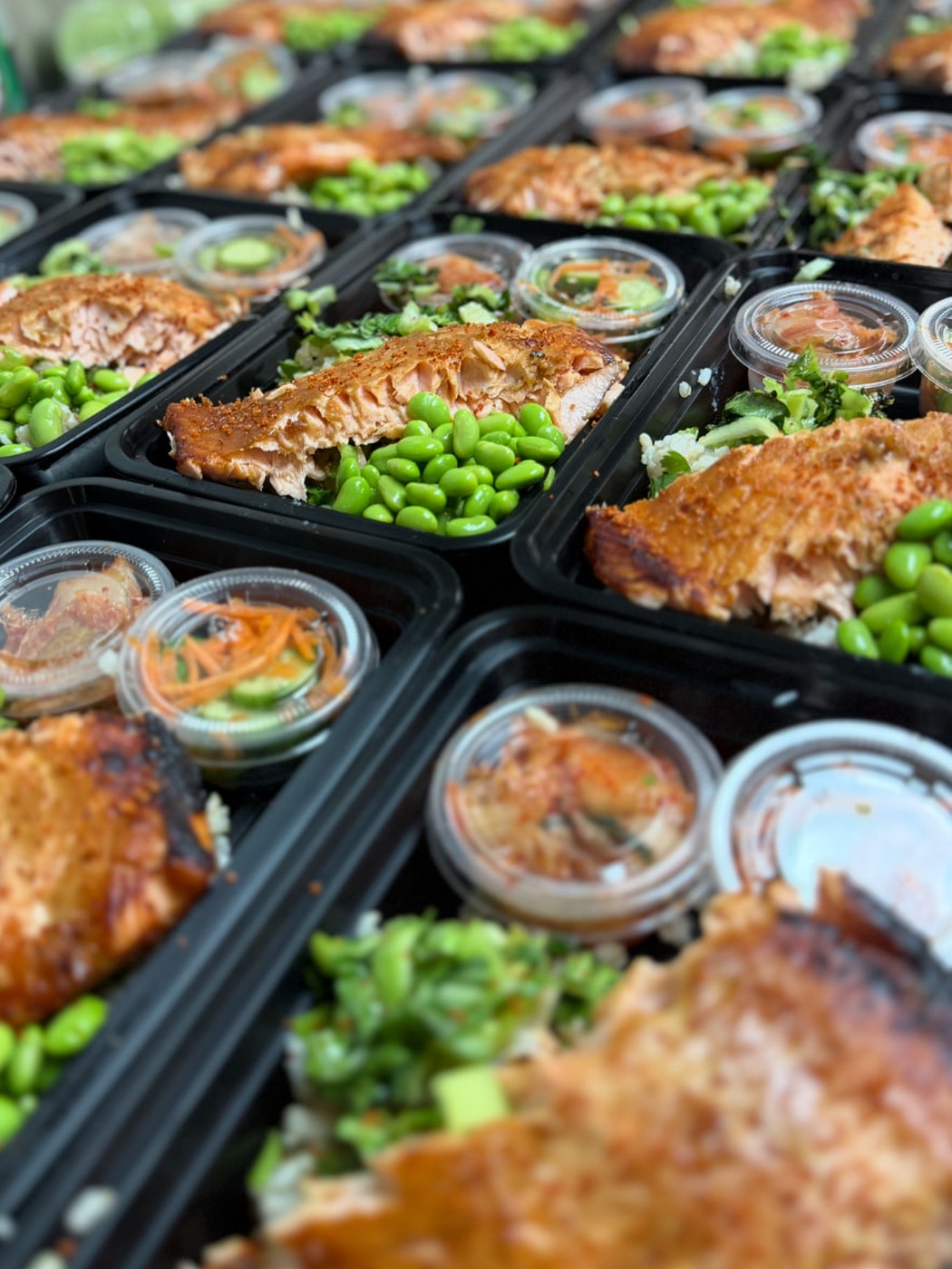 Salmon meal prep containers with edamame rice and dipping sauces
