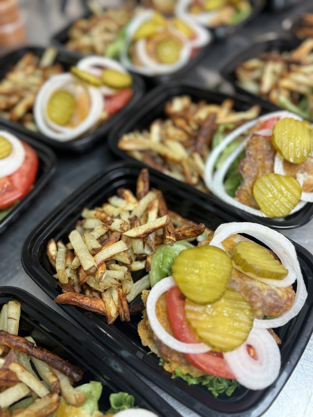 Crispy chicken sandwiches with hand-cut fries in meal prep trays